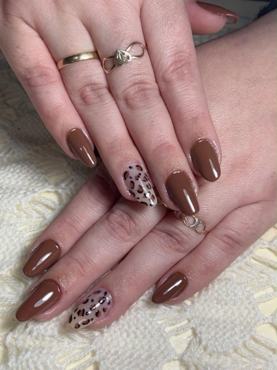 Unhas em formato amêndoa esmaltadas em marrom café com duas unhas de destaque em animal print pintado à mão