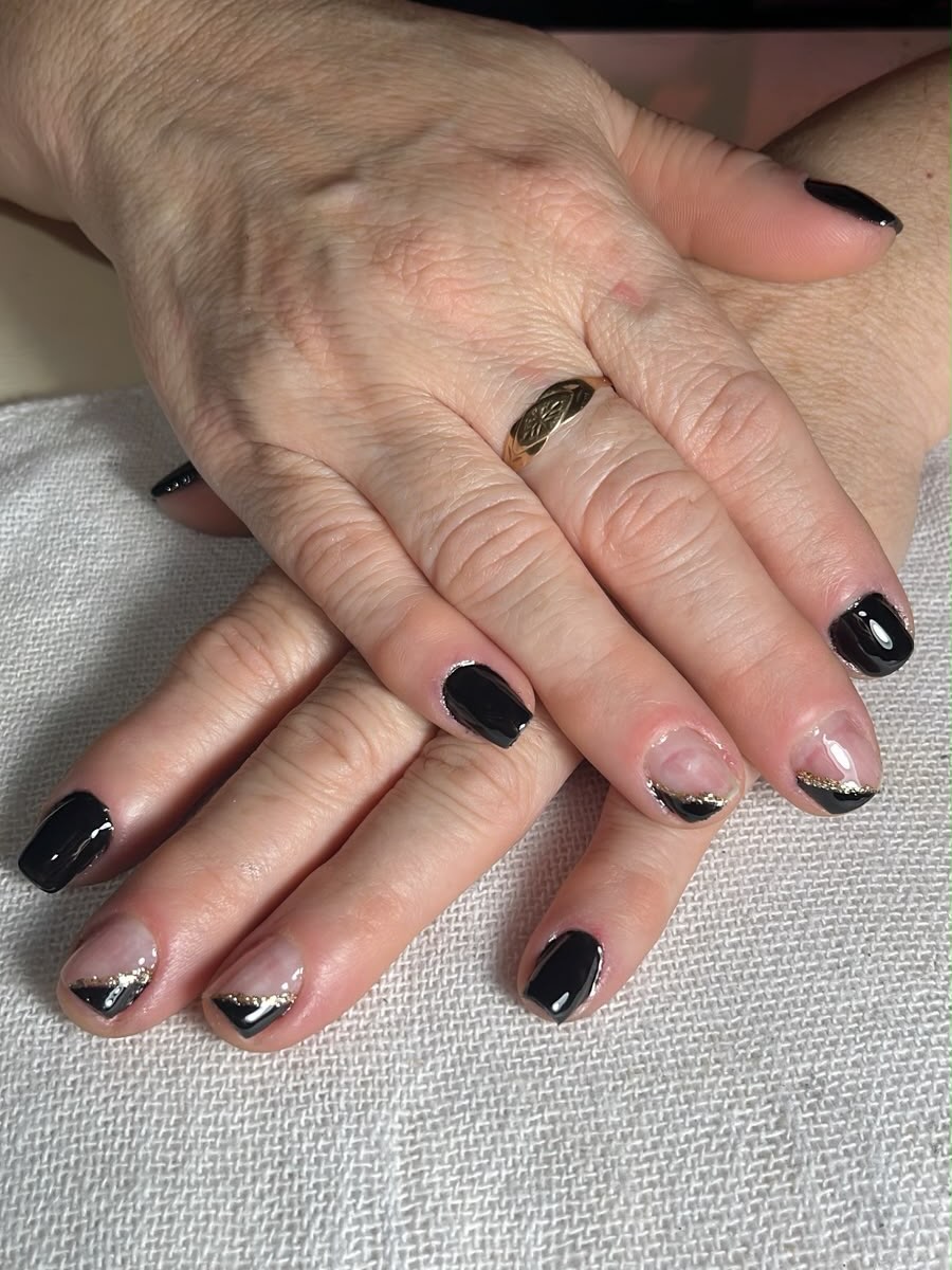 Unhas curtas em preto com francesinha diagonal e fio dourado nas unhas de destaque