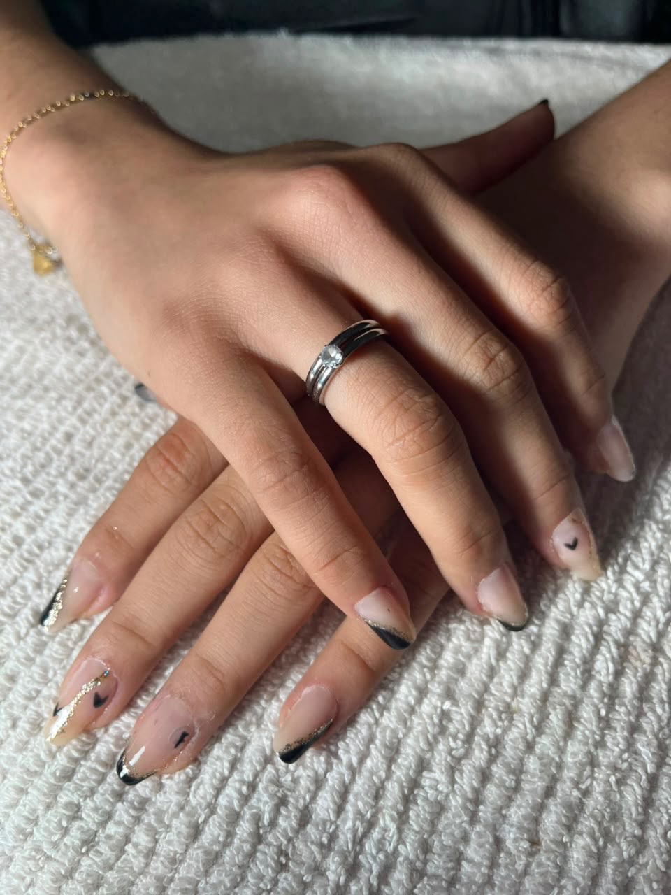 Unhas nude com ponta preta diagonal, fio de glitter dourado e coraçõezinhos desenhados